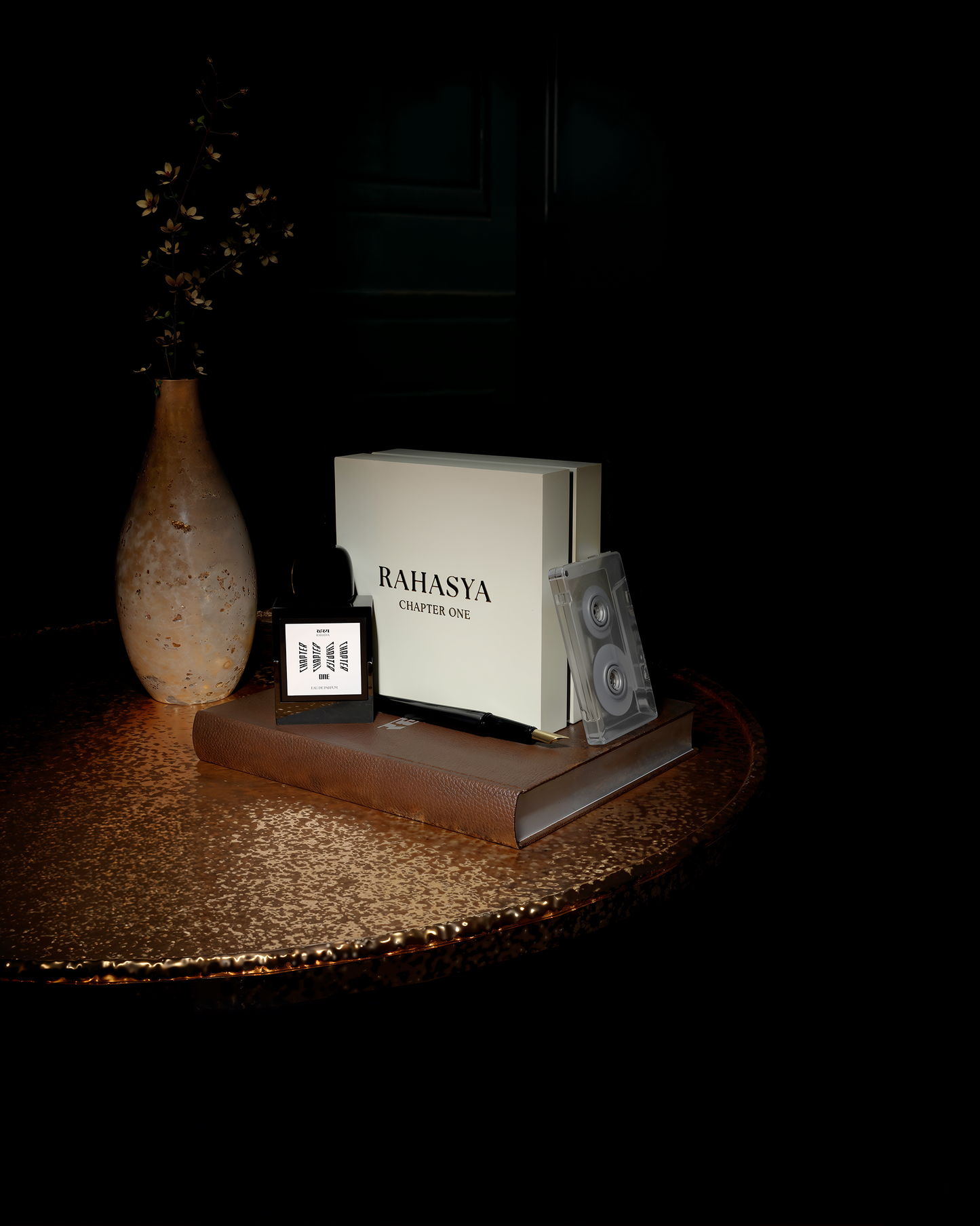 Close up shot of Rahasya Fragrances Chapter One perfume bottle and packaging atop an aged leather bound book